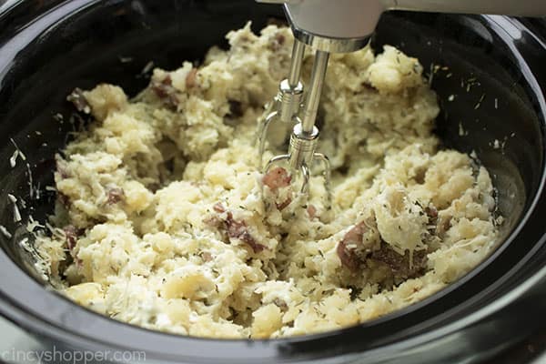Hand mixer mixing potatoes in slow cooker