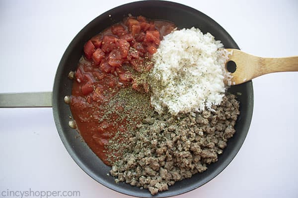 Spices, rice and tomatoes added to pan