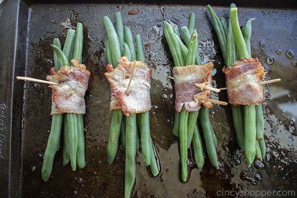 Bacon wrapped around green beans on a sheet pan