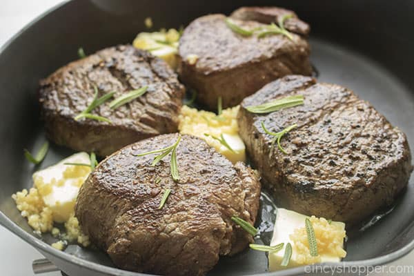 Pan seared filet mignon steaks in pan with butter, garlic and rosemary