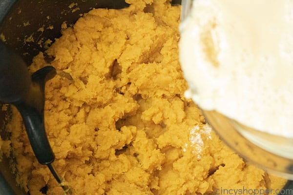 Adding cream mixture to mashed potatoes