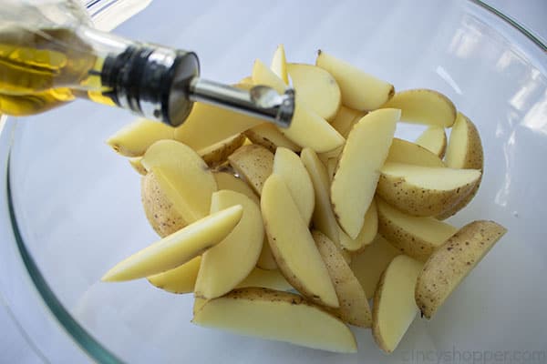 Adding oil to potato slices 
