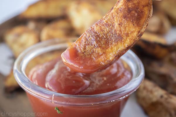 Seasoned potato wedges dipped in ketchup