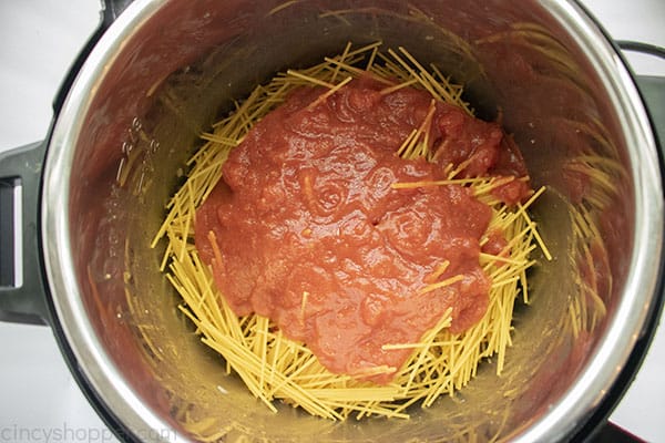 Tomatoes added on the top of uncooked spaghetti