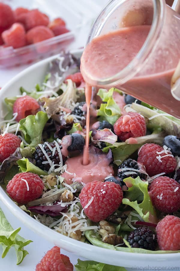 Raspberry Vinaigrette salad dressing pouring on berry salad