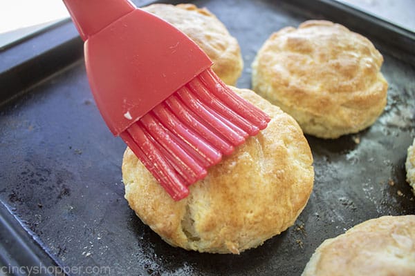 Buttering the tops of homemade biscuit