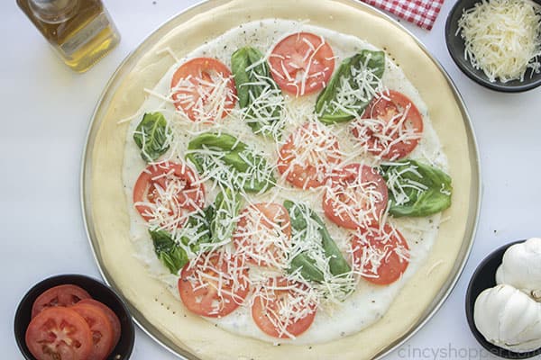 White sauce on pizza dough, basil and tomatoes added