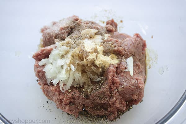 Ground beef, onions and spices in a bowl