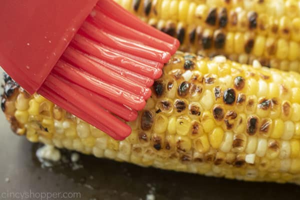 Brushing garlic butter onto corn on the cob
