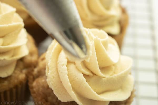 Adding caramel frosting to apple cupcake