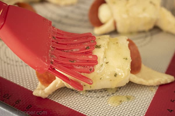 Brushing butter on top of appetizer crescents