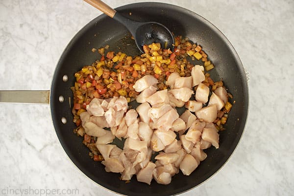 Raw chicken added to veggies and spices