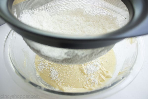 Sifting powder sugar into cream cheese