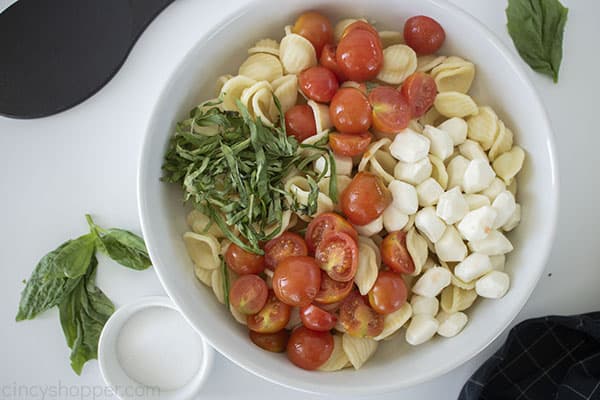 Pasta, basil, tomatoes and cheese in a bowl