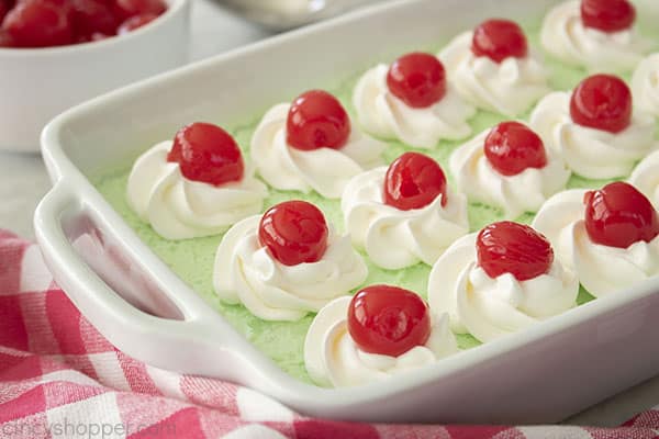 Whipped cream and cherries added to lime jello dessert