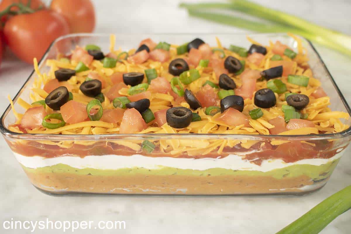 Finished Mexican layered dip in a clear dish.