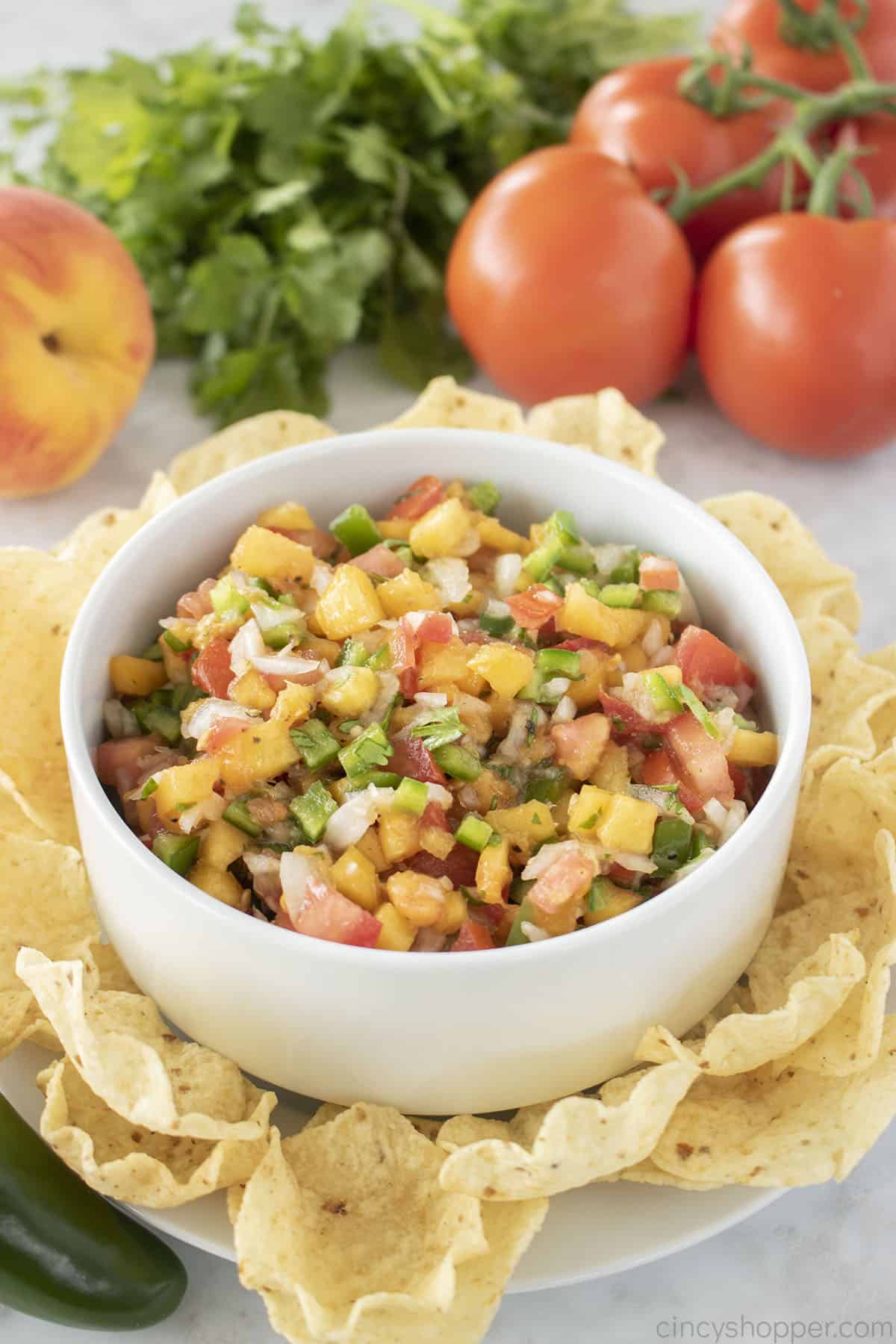 Peach Salsa in a white bowl with tortilla chips.