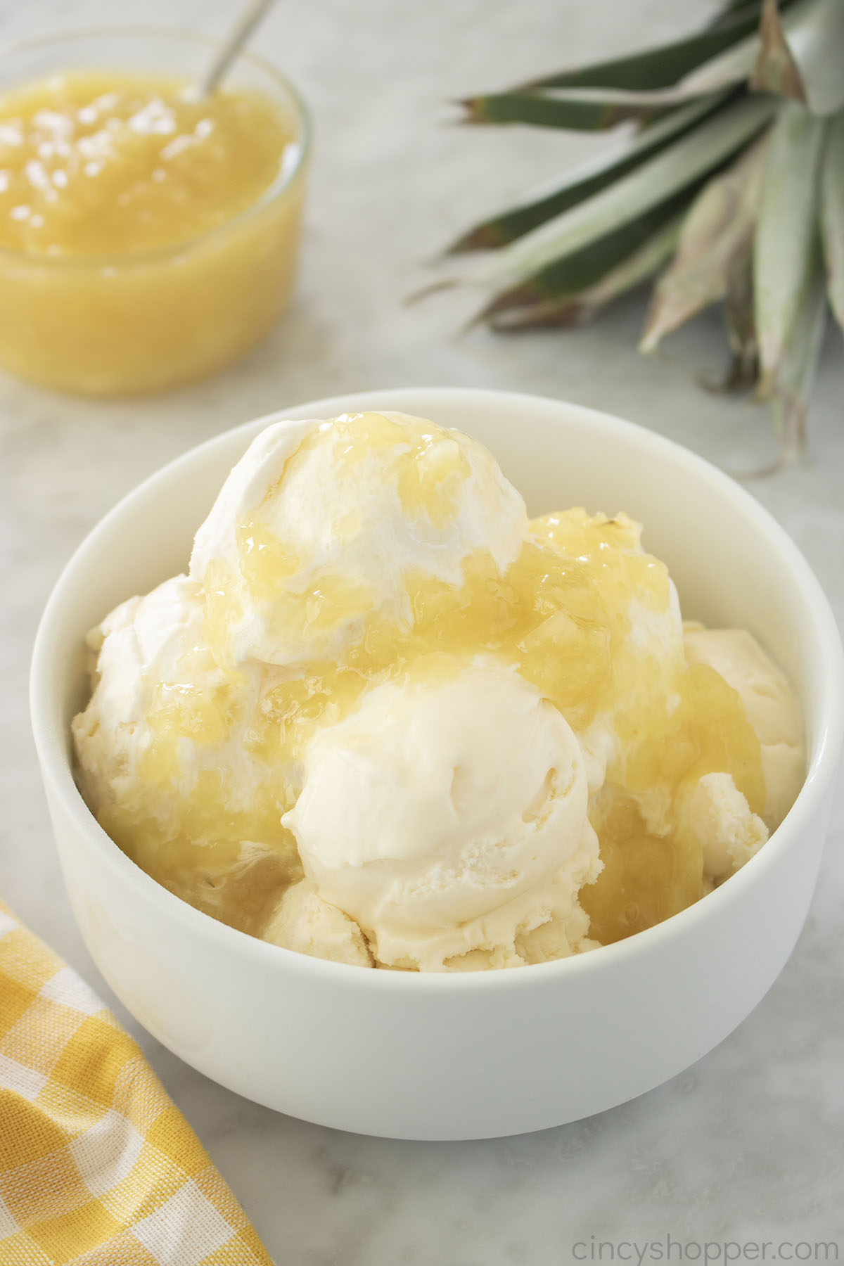 Pineapple Sauce on vanilla ice cream in a white bowl.