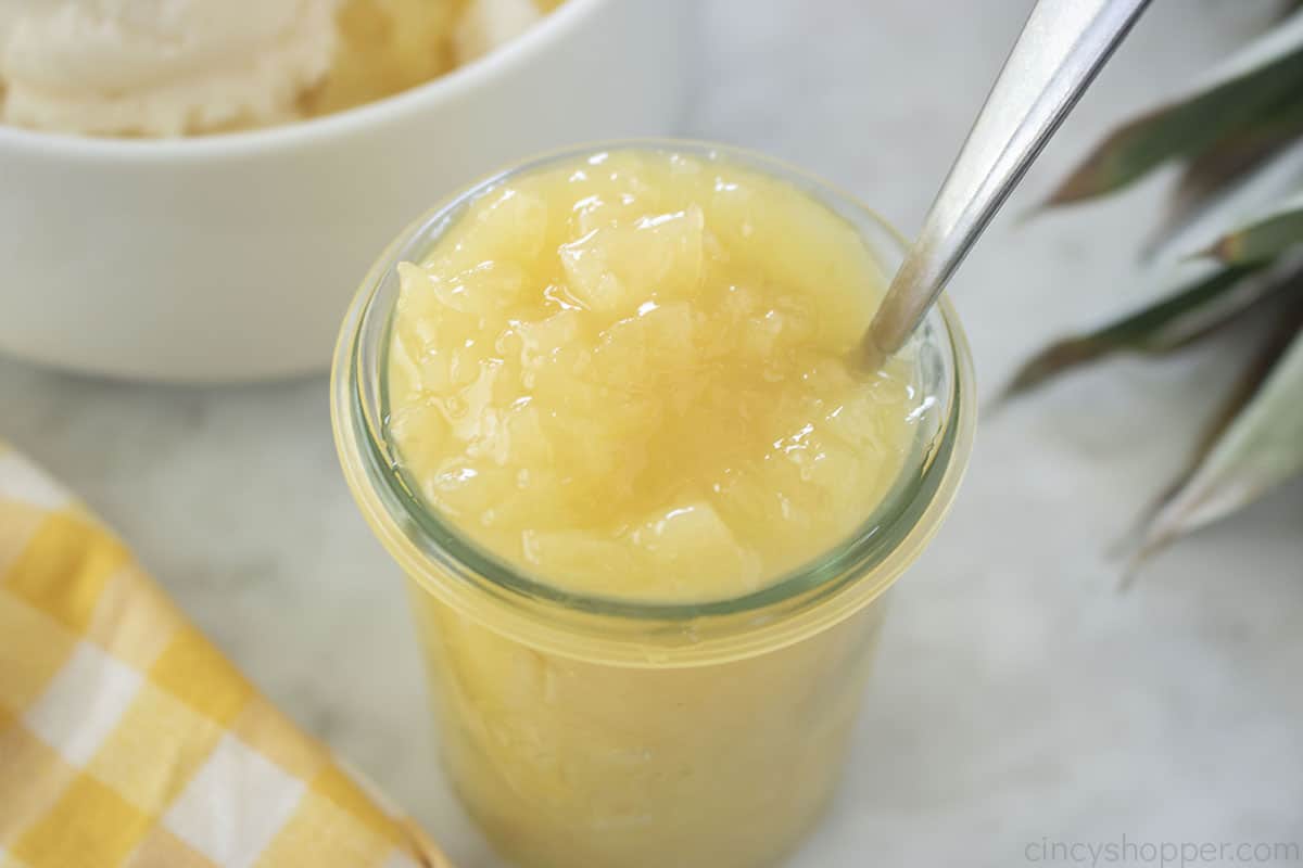 Pineapple topping in a jar with a spoon.