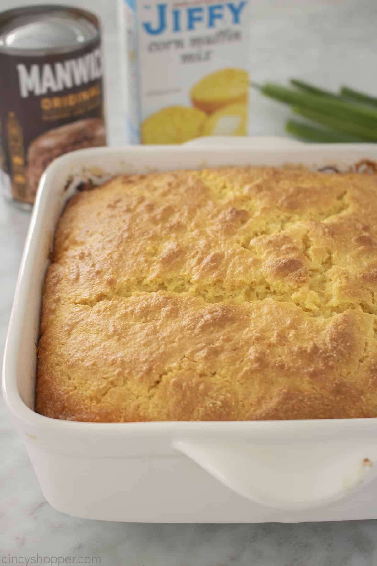 White Casserole dish with Sloppy Joe and cornbread.