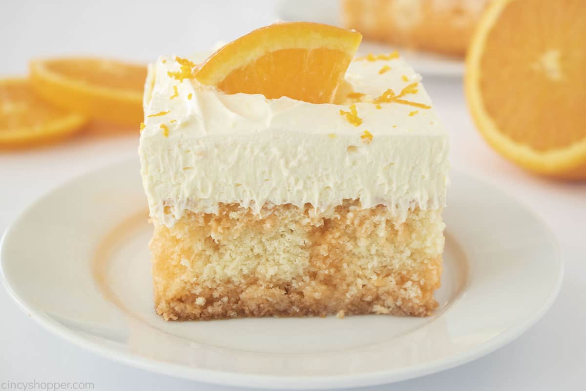 Orange Creamsicle Poke Cake slice on a white plate.