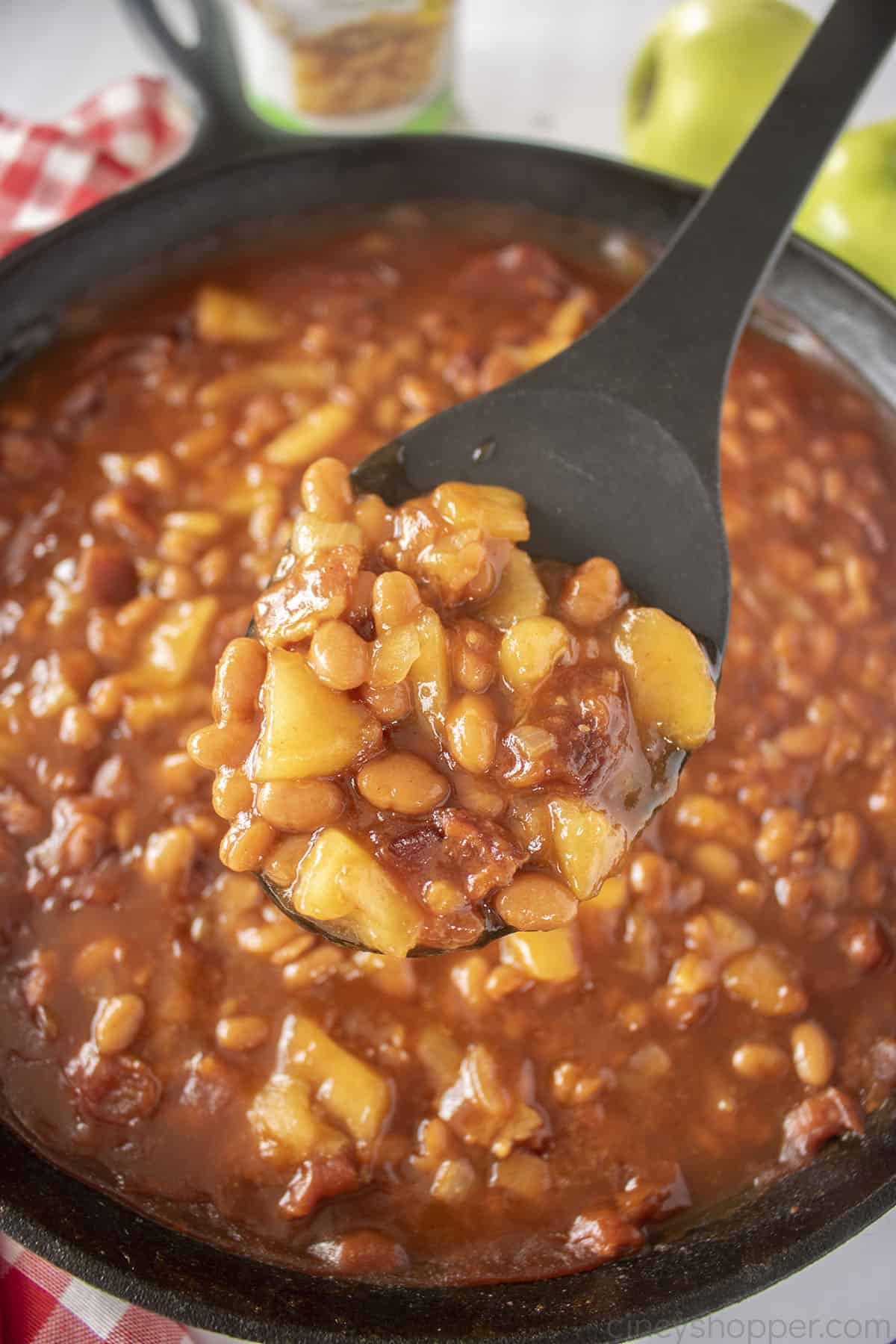 Apple baked beans on a black spoon.