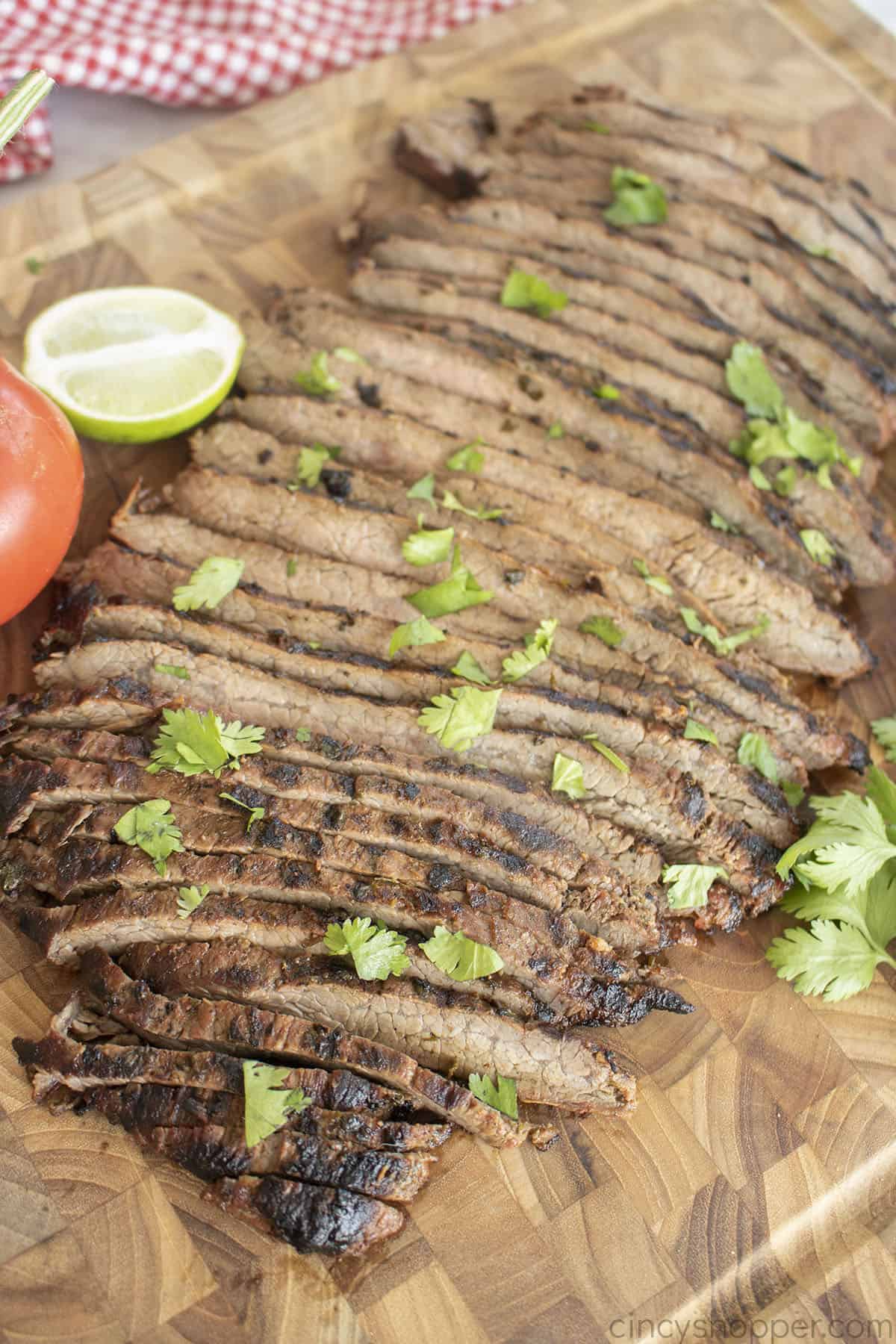 Sliced flank steak for tacos on a cutting board.