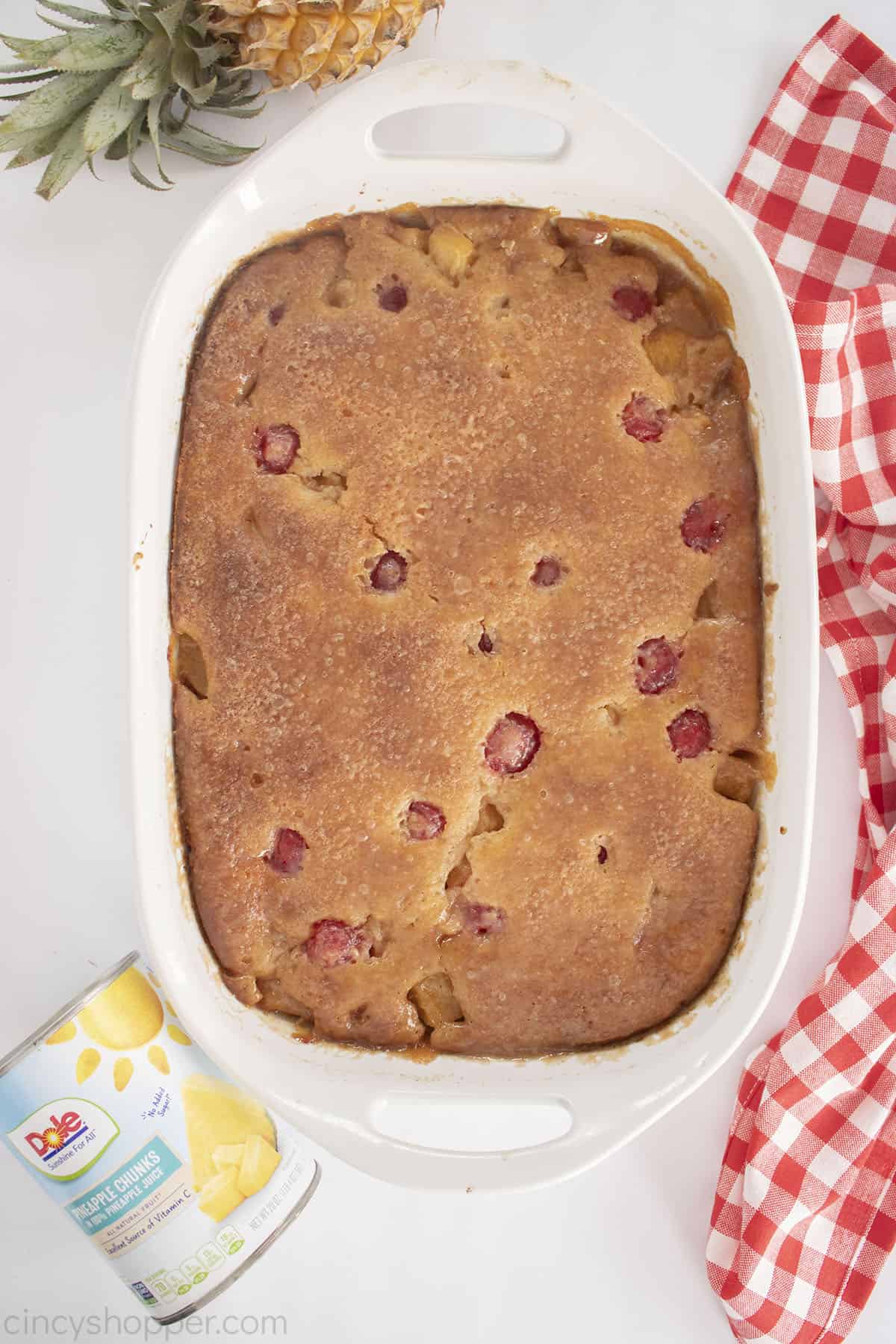 White baking dish with baked pineapple and cherry cobbler.