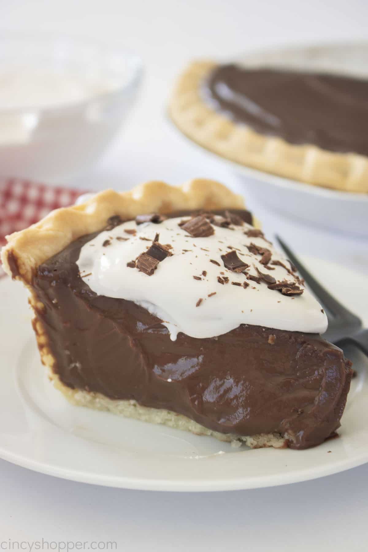 Slice of Chocolate Pudding Pie with whipped cream and chocolate shavings.