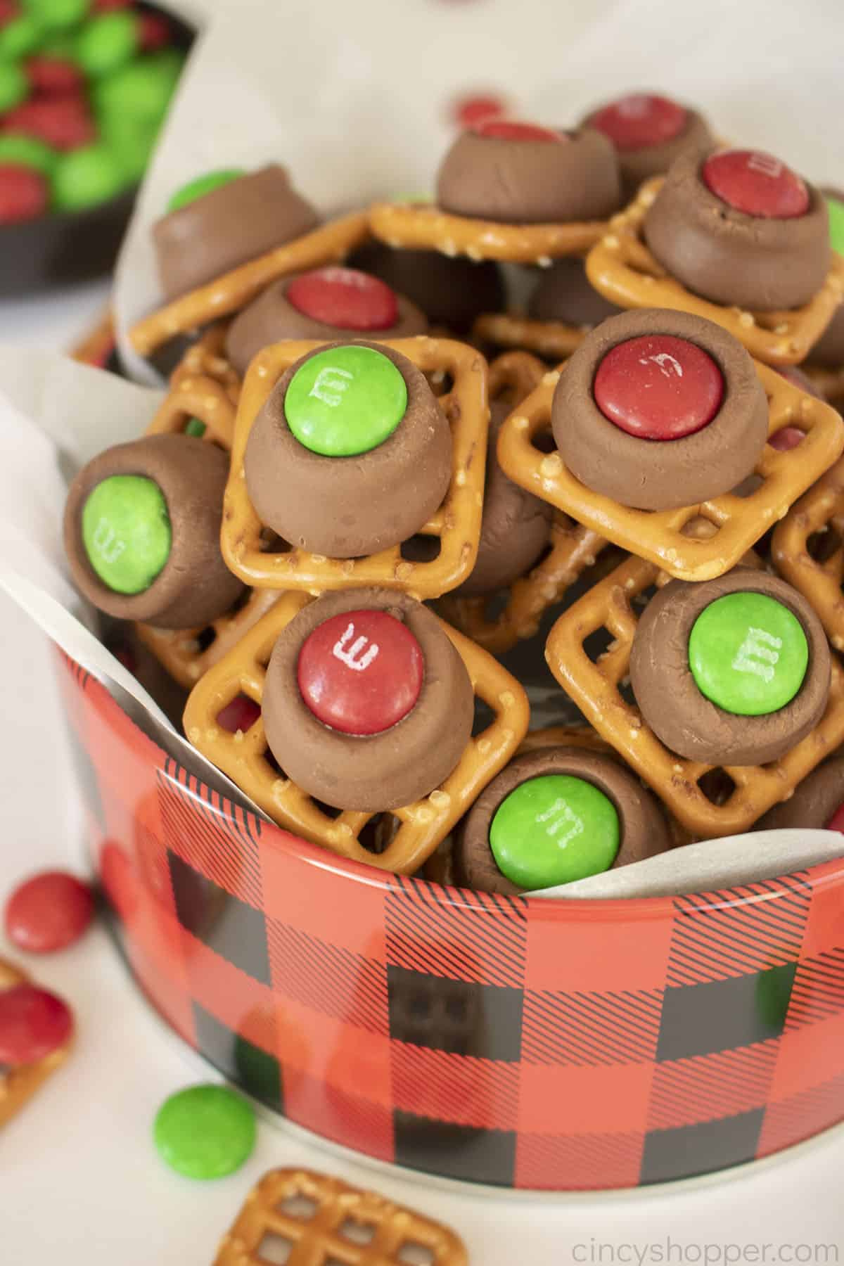 Pretzels with melted Hershey Kiss Candies and holiday M&M's in a gifting tin.