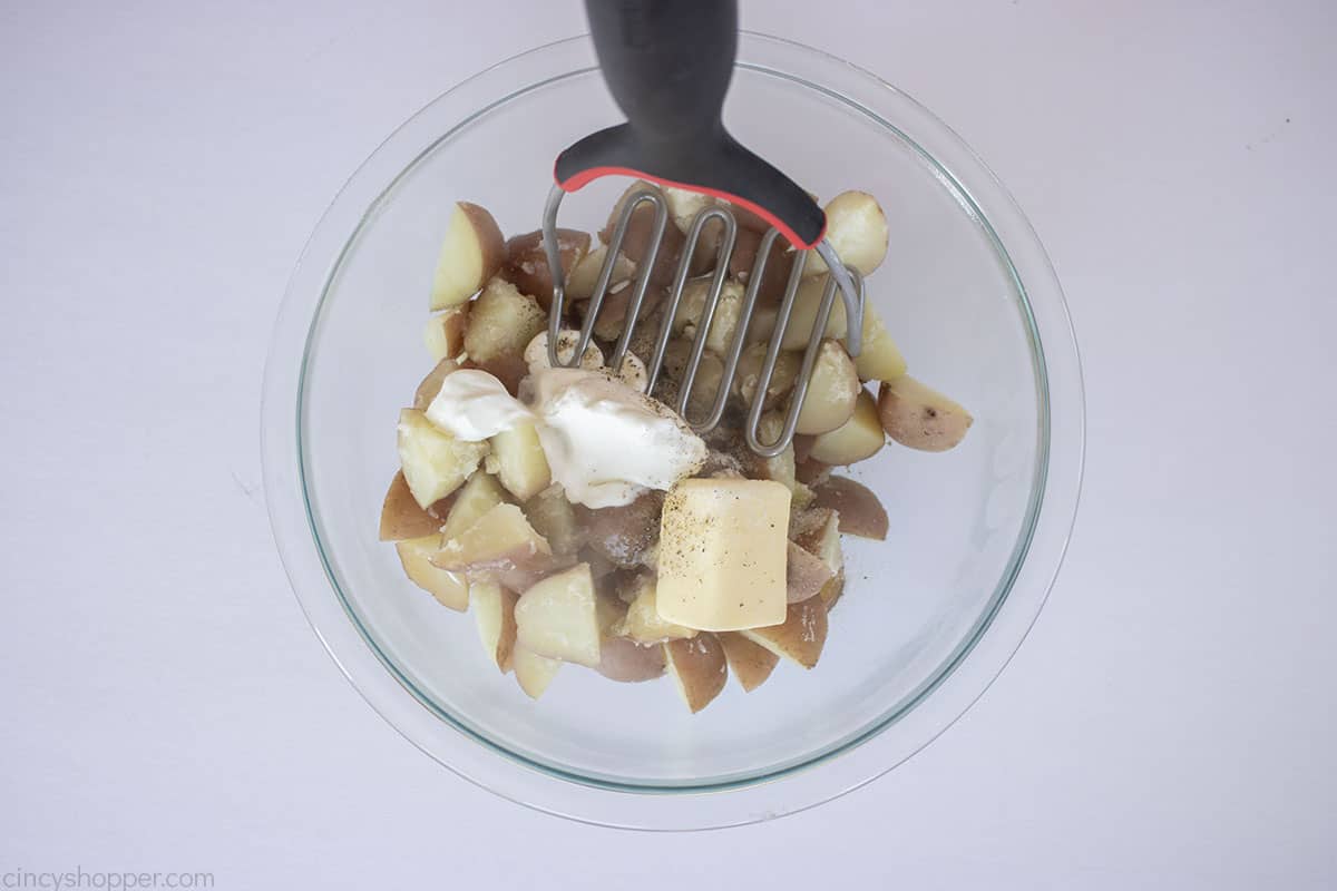 Mashing red skin potatoes with sour cream, butter, milk.