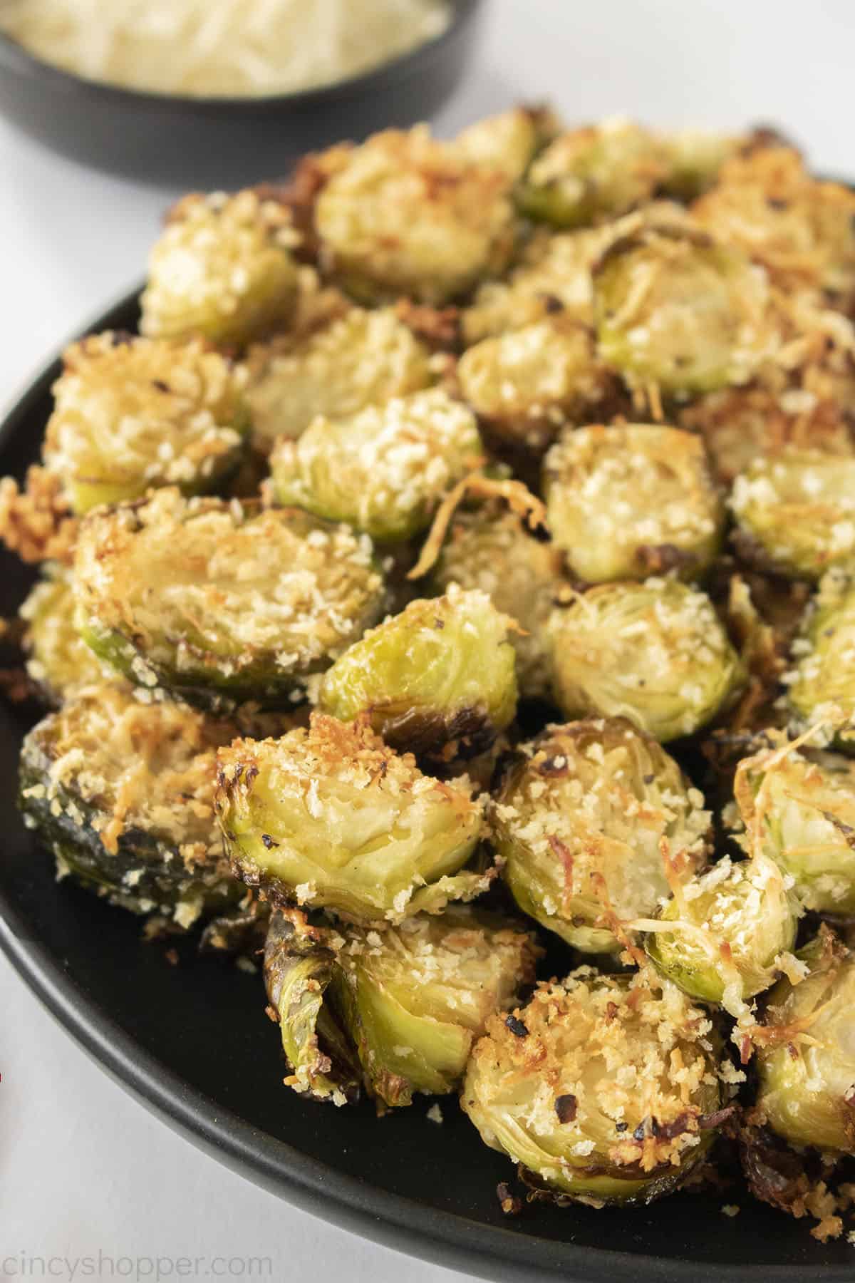 Parmesan Crusted Brussel Sprouts on  a black plate.