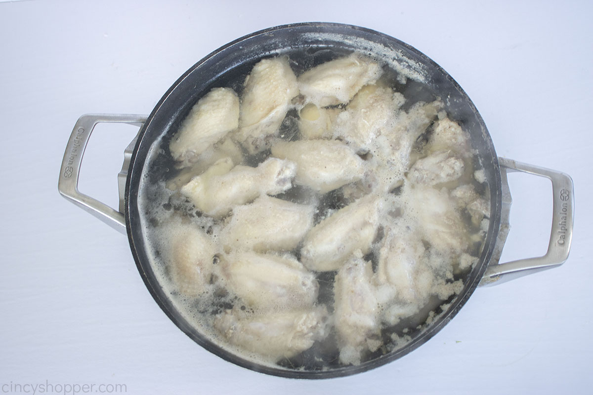 Chicken wings in a pot with boiled water.