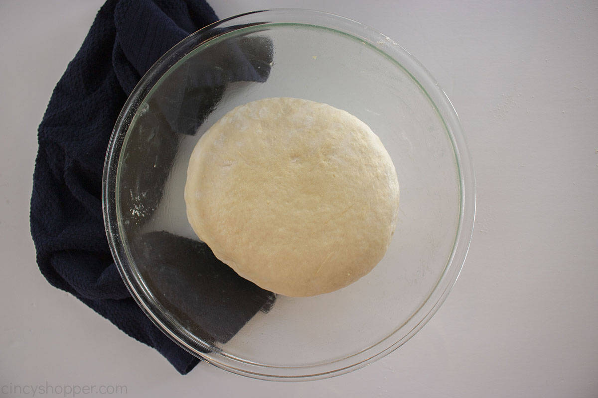 Half risen dough in a clear bowl.