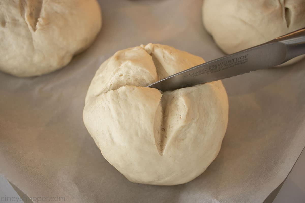 Knife cutting an x into the the dough bowls.