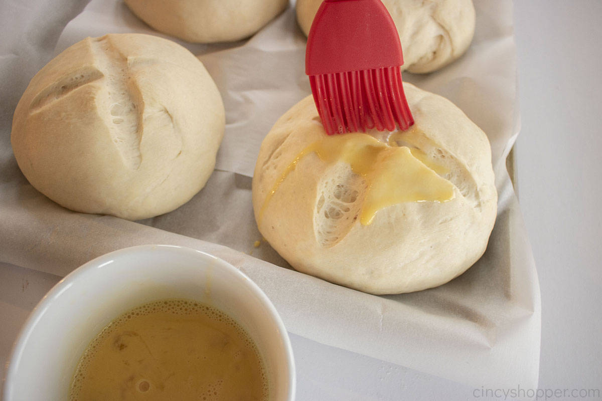 Adding egg wash to bread bowls before baking.
