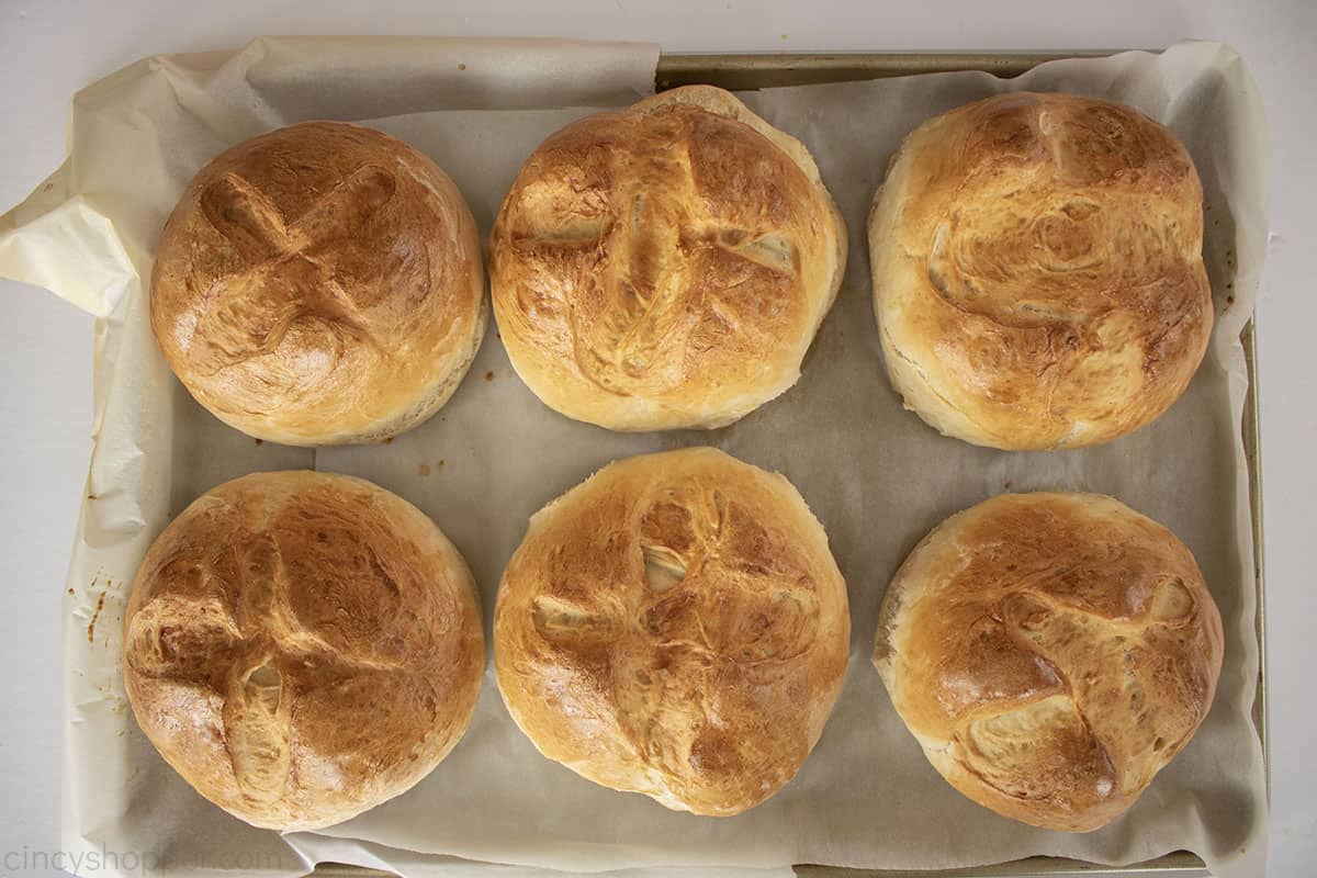 Baked bread bowls on a parchment lined baking pan.