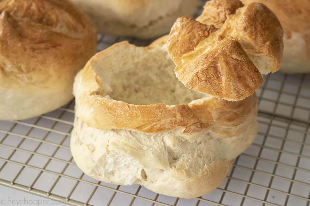 Baked bread bowl with lid on a cooling rack.