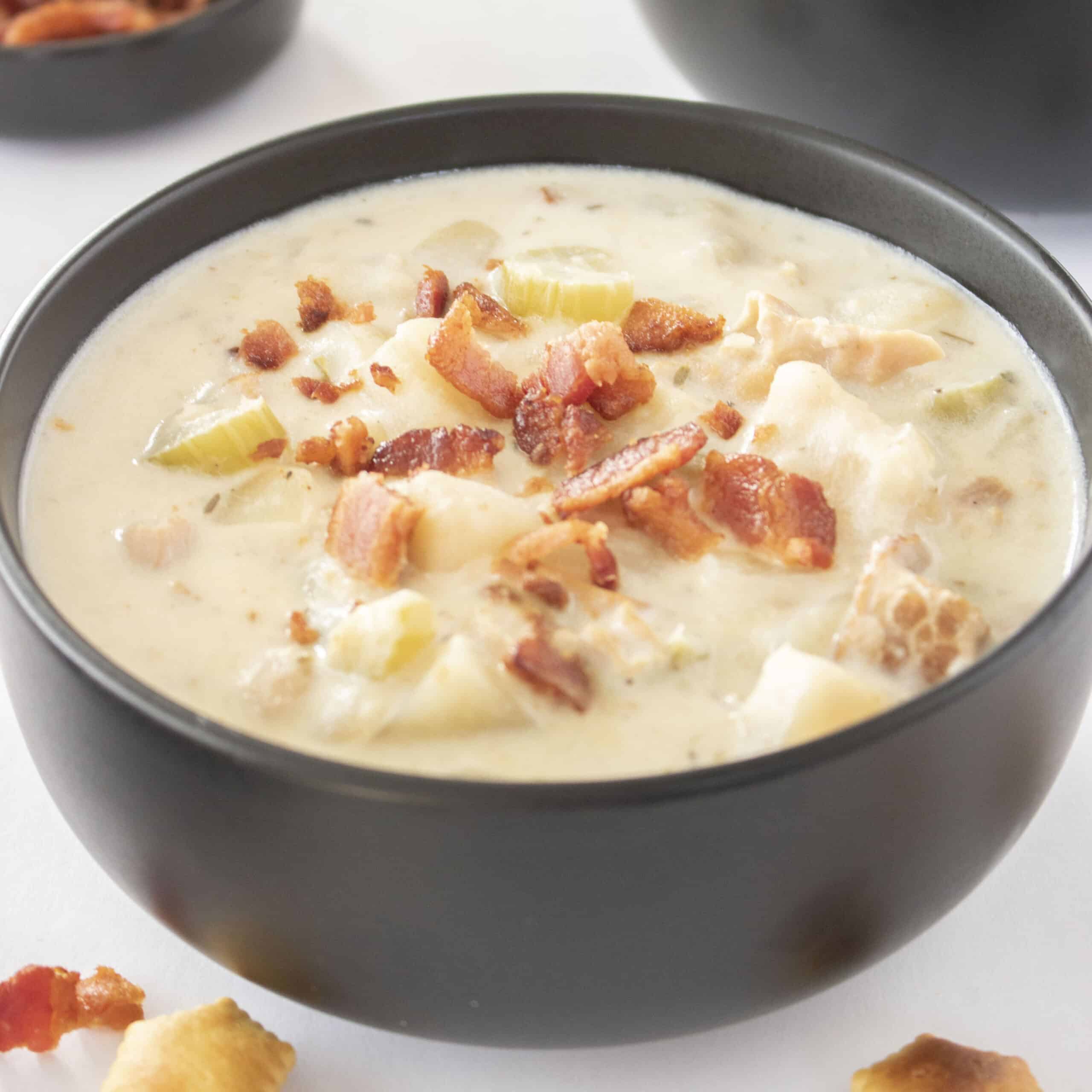 Crock Pot Clam Chowder in a black bowl topped with bacon pices.
