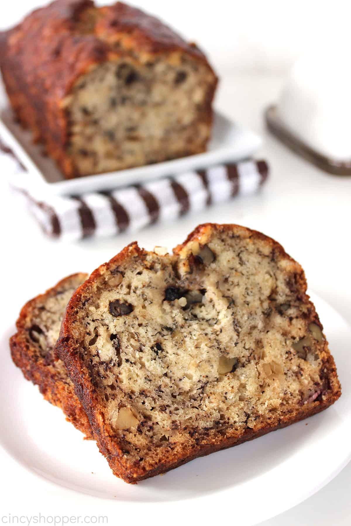Sliced banana bread with loaf in the background.