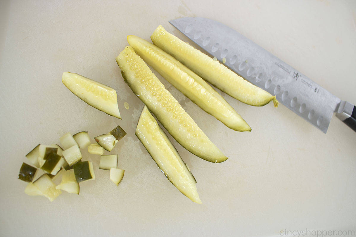 Diced pickles on a cutting board with a knife.