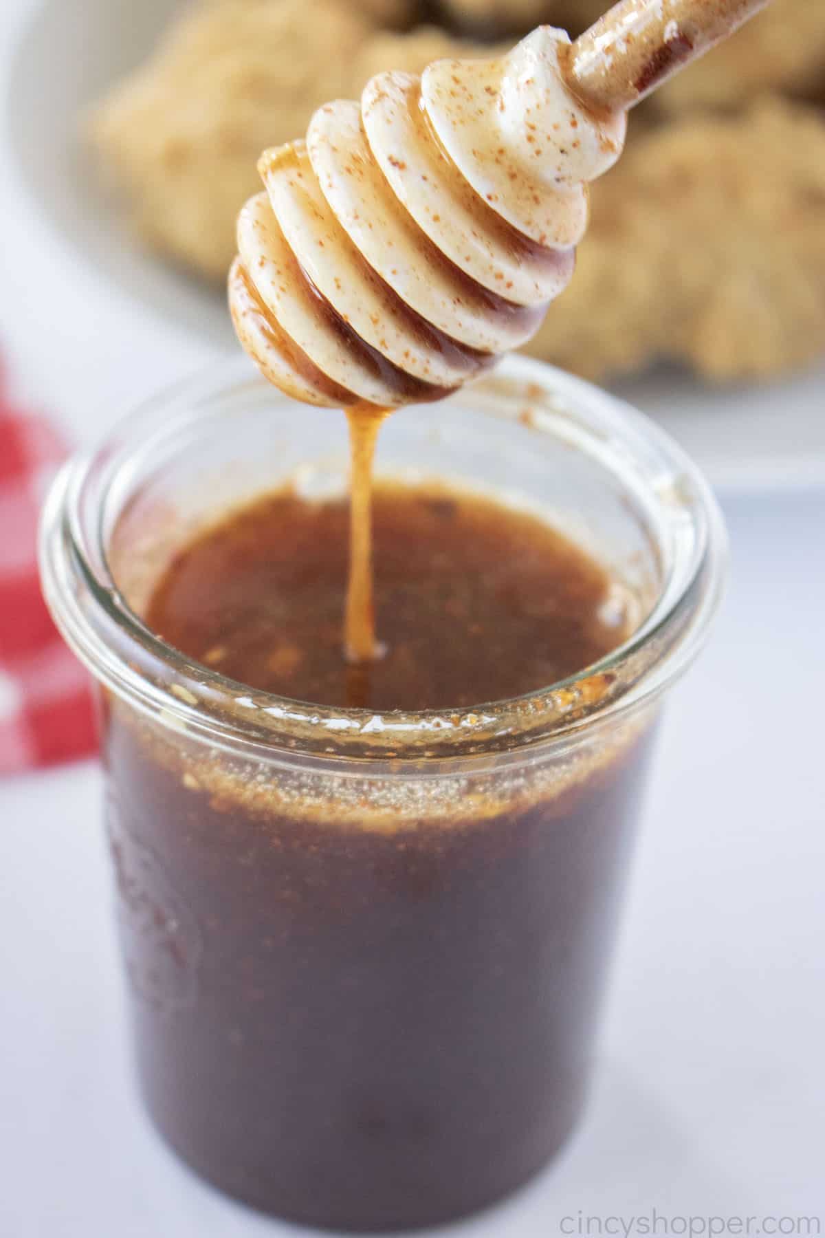 Hot Honey Sauce in a jar with a honey dipper.