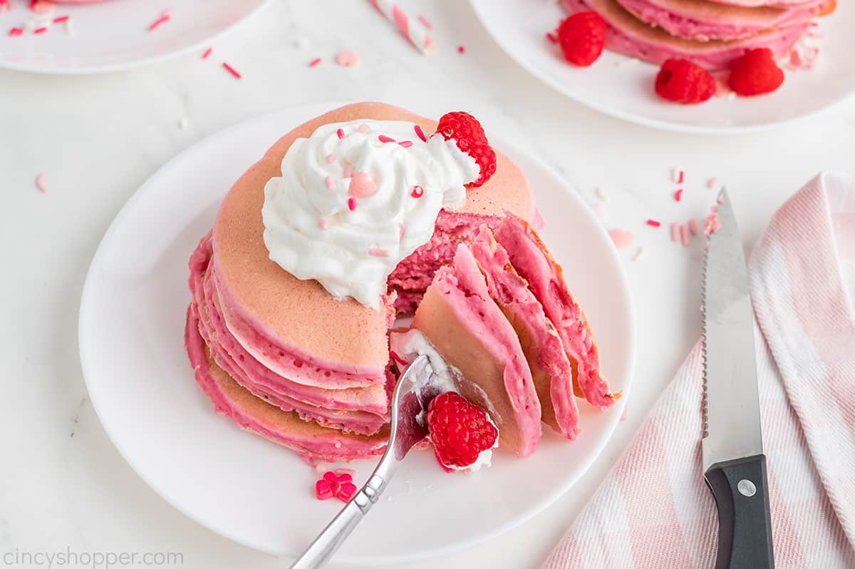 Fork cut of pink pancakes on a plate.