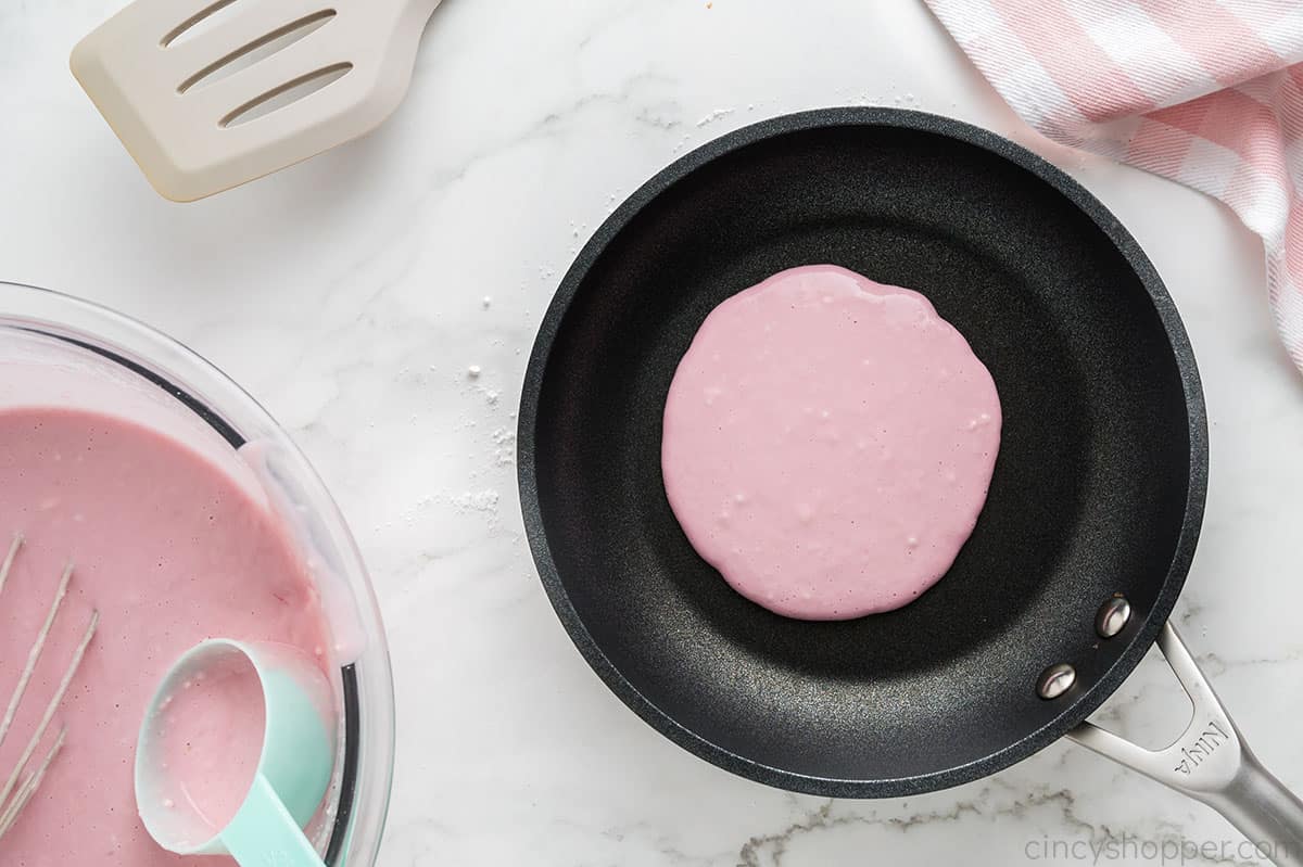 Pink pancake in a non stick pan.