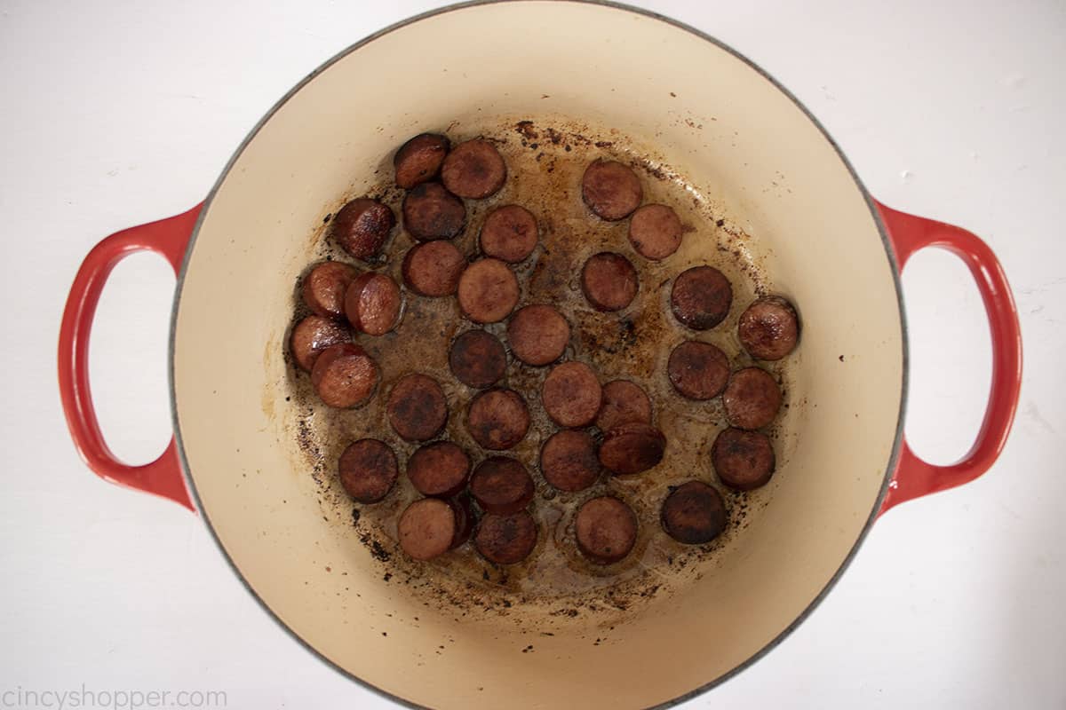 Cooked kielbasa in a red dutch oven.
