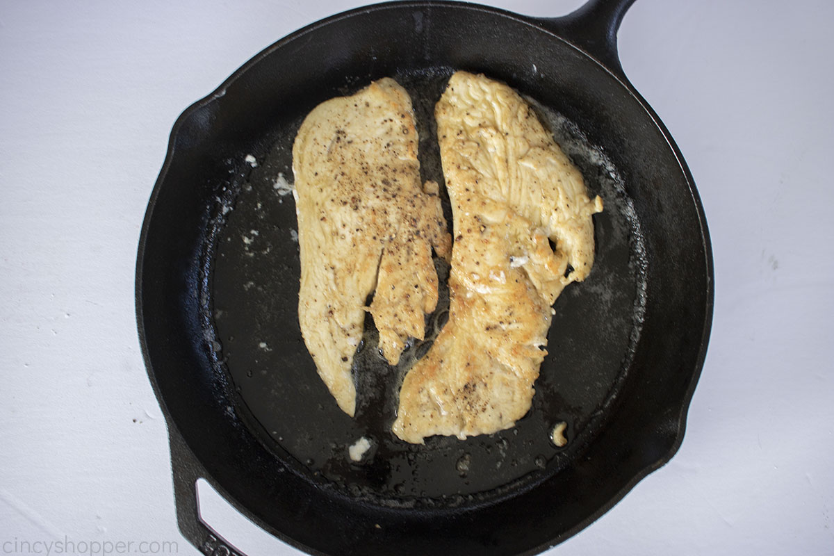 Pan fried chicken breast in a cast iron skillet for Marsala Chicken.