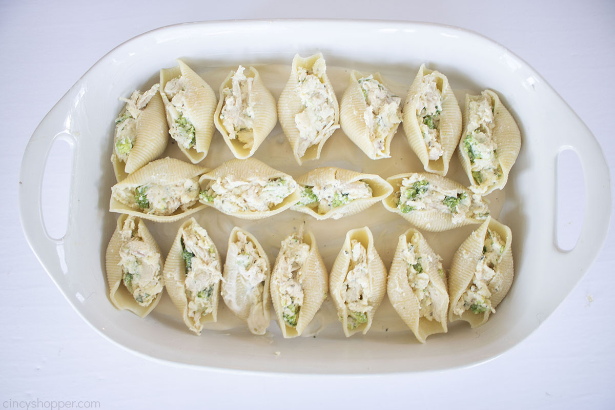 Stuffed shells with chicken and broccoli in a white baking dish.