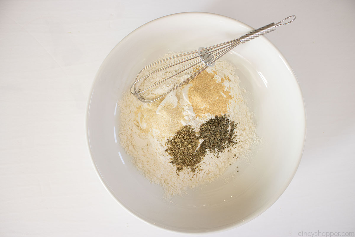 Flour and spices in a white bowl with a whisk.