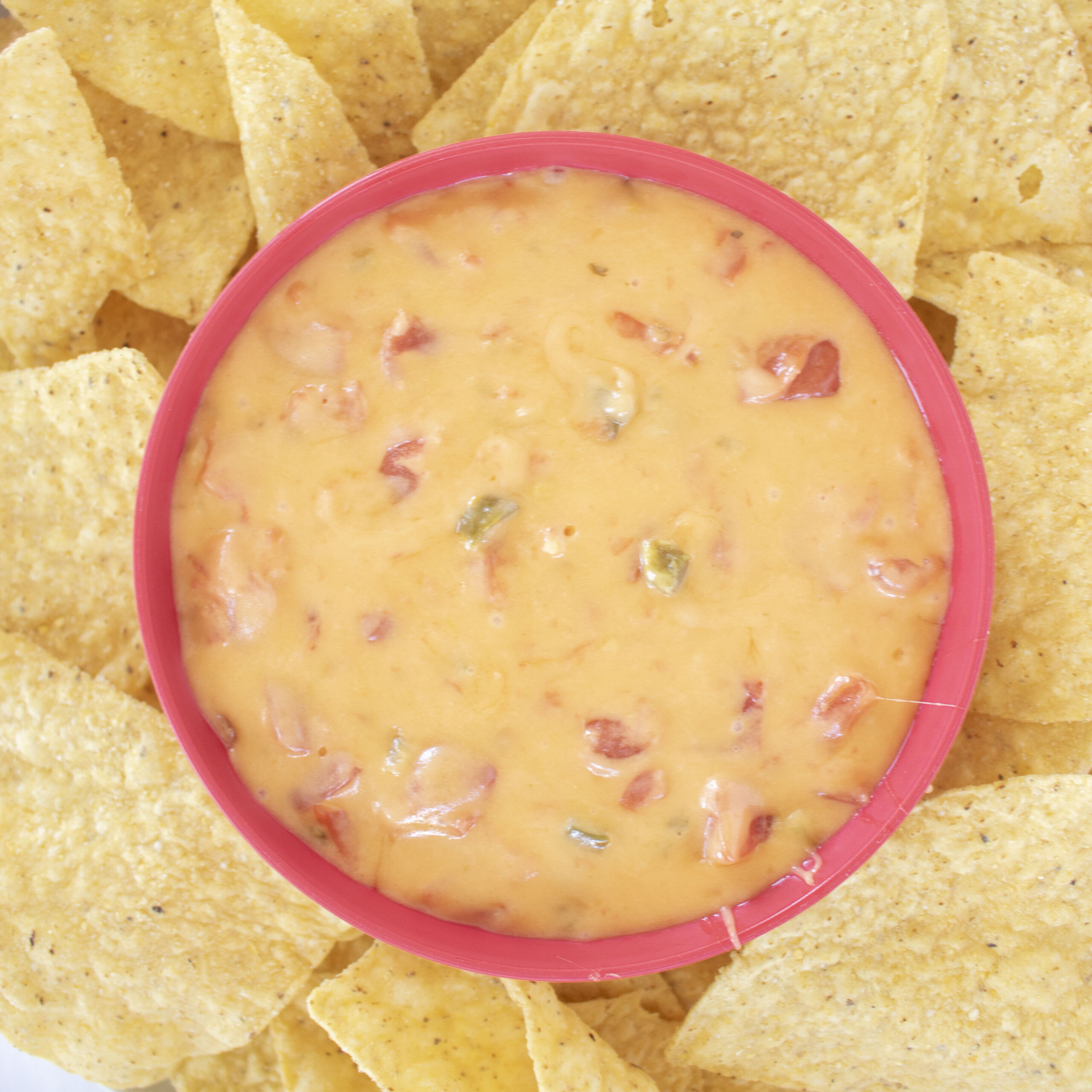 Salsa Con Queso in a red bowl with tortilla chips.