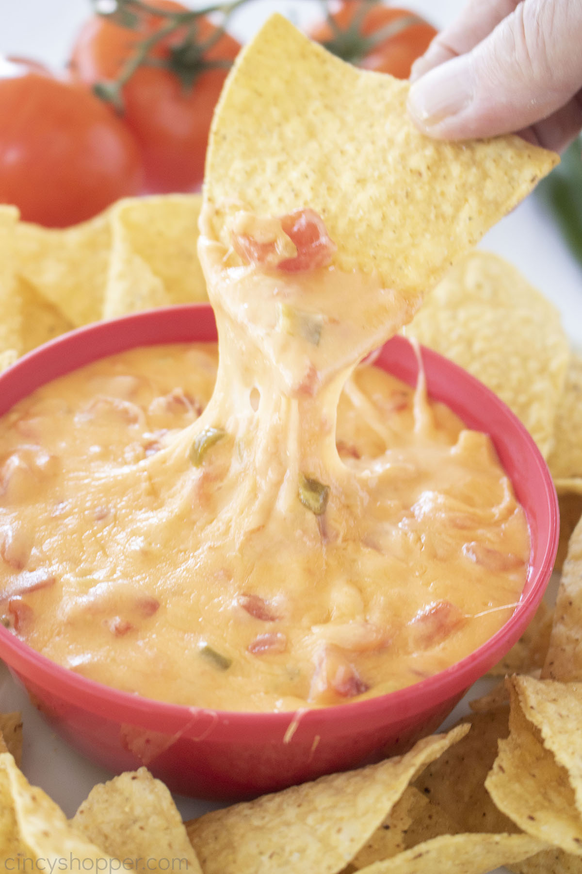 Cheesy Queso dip with salsa on a tortilla chip.